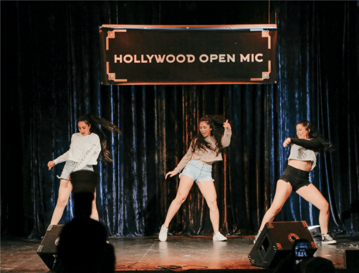 Performers dancing on a stage under an "Open Mic" sign